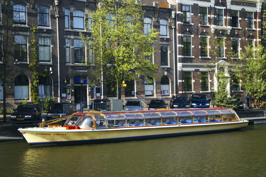Netherlands, North Holland, Amsterdam. Canal cruise ship situated on the River Amstel in Amsterdam City.