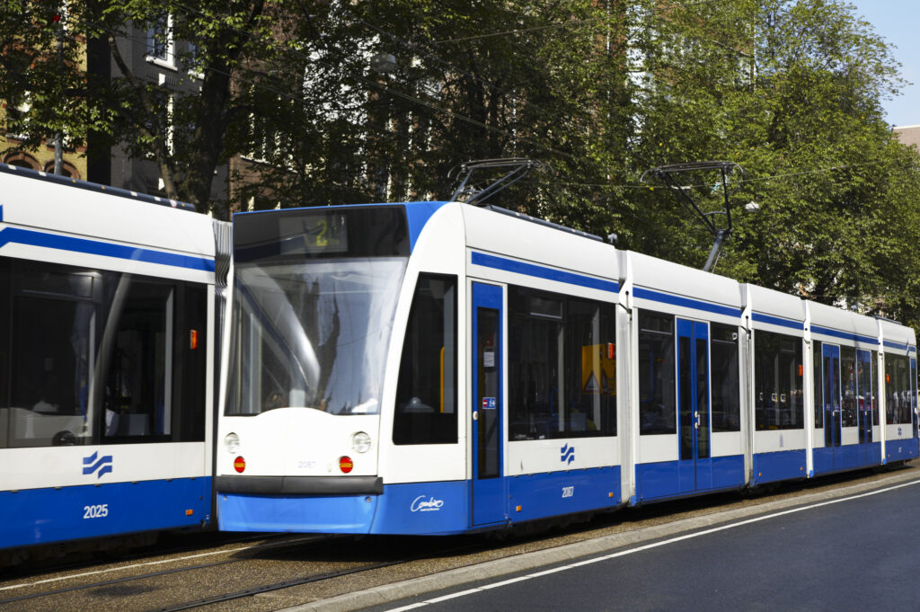 Netherlands, North Holland, Amsterdam. Public transport train tram running along a road in Amsterdam City.
