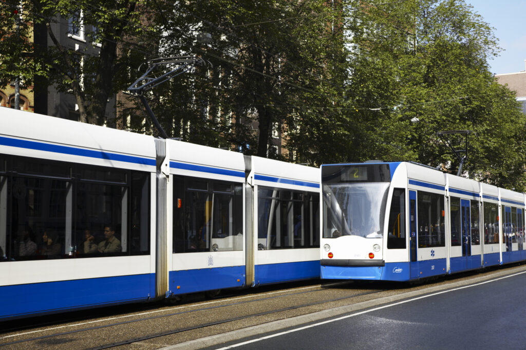 Netherlands, North Holland, Amsterdam. Public transport train tram running along a road in Amsterdam City.