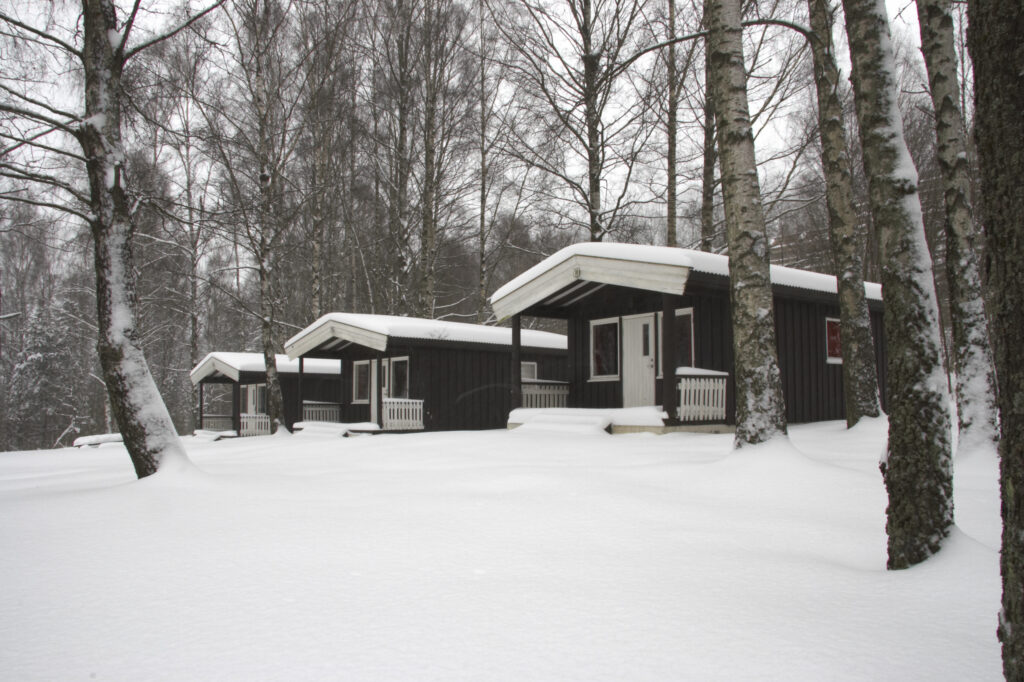 Norway, Oslo, Oslo City. Snow covered wooden camping huts / cabins in the Bogstad camping ground in Oslo city.
