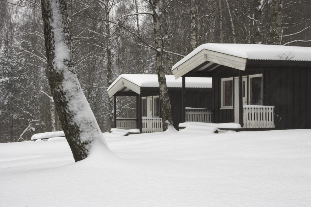Norway, Oslo, Oslo City. Snow covered wooden camping huts / cabins in the Bogstad camping ground in Oslo city.