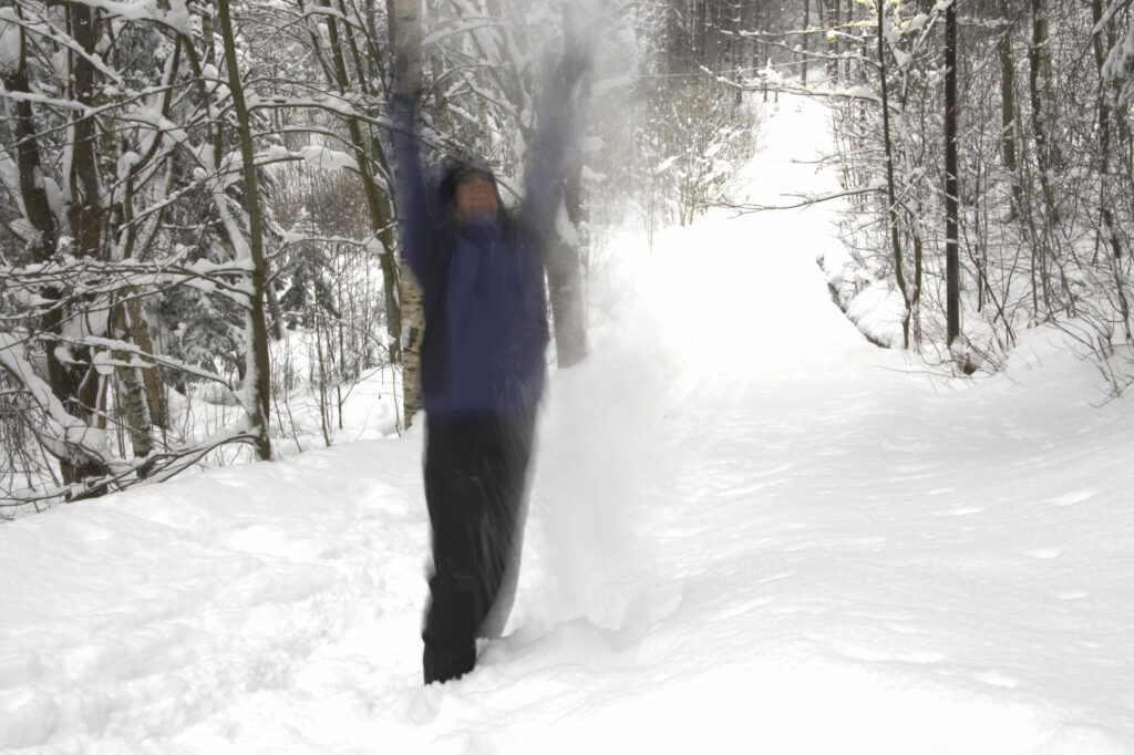 Norway, Oslo, Oslo City. Hiker throwing snow in the air, in snow covered woodland in Oslo Forest near Bogstad Camping.