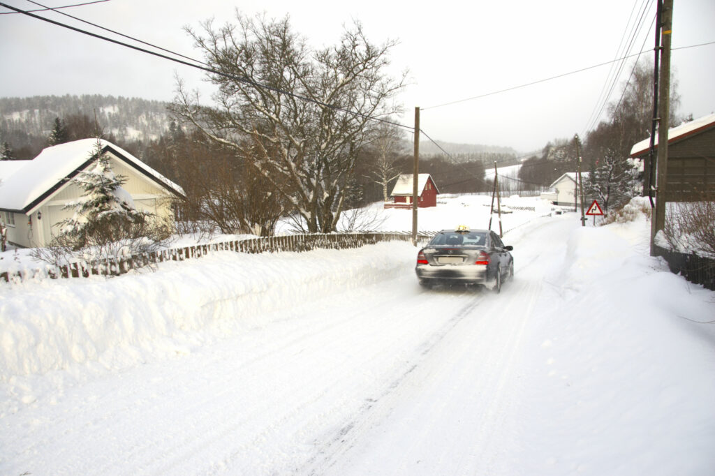 Norway, Oslo, Oslo City. Car driving down a country road after a heavy snowfall near the Tryvann Ski field in the Oslo forest.