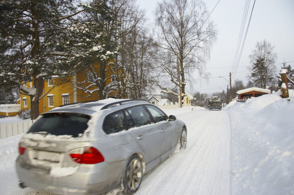 Norway, Oslo, Oslo City. Car driving down a country road after a heavy snowfall near the Tryvann Ski field in the Oslo forest.