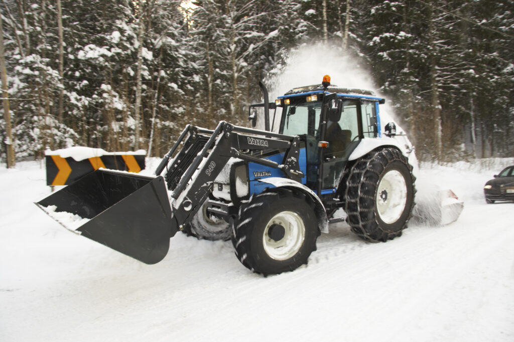 Norway, Oslo, Oslo City. Snow plough / tractor driving down a country road after a heavy snowfall near the Tryvann Ski field in the Oslo forest.