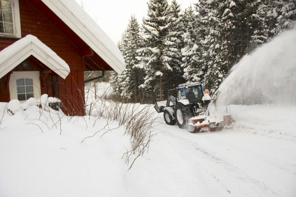 Norway, Oslo, Oslo City. Snow plough / tractor driving down a country road after a heavy snowfall near the Tryvann Ski field in the Oslo forest.