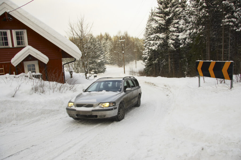 Norway, Oslo, Oslo City. Car driving down a country road after a heavy snowfall near the Tryvann Ski field in the Oslo forest.