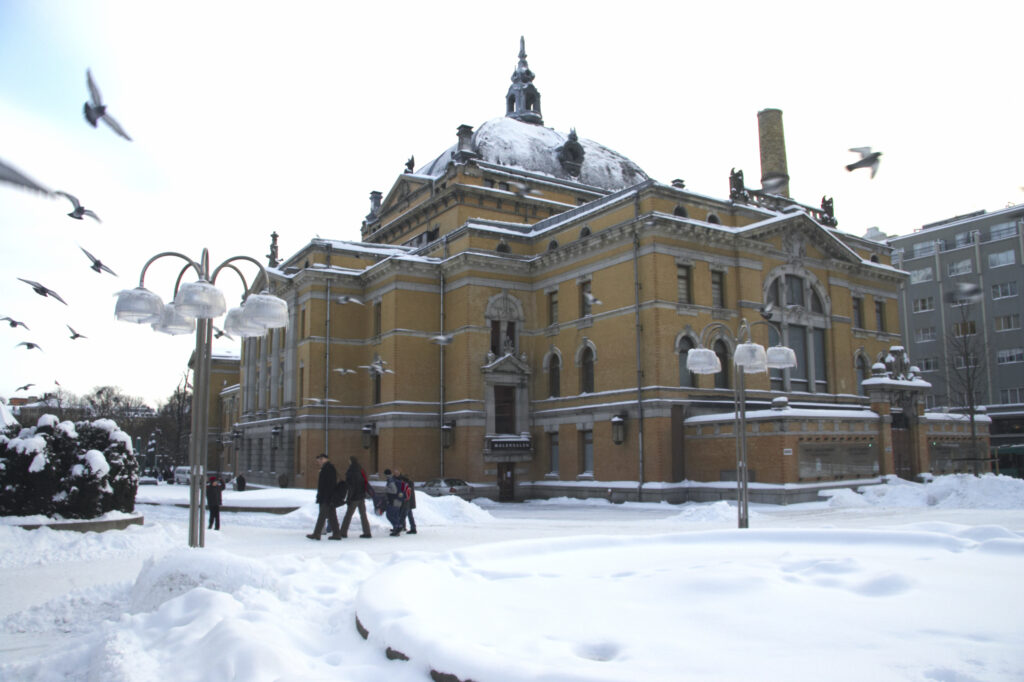 Norway, Oslo, Oslo City. Birds flying near to the National theatre, surrounded by a covering of snow.