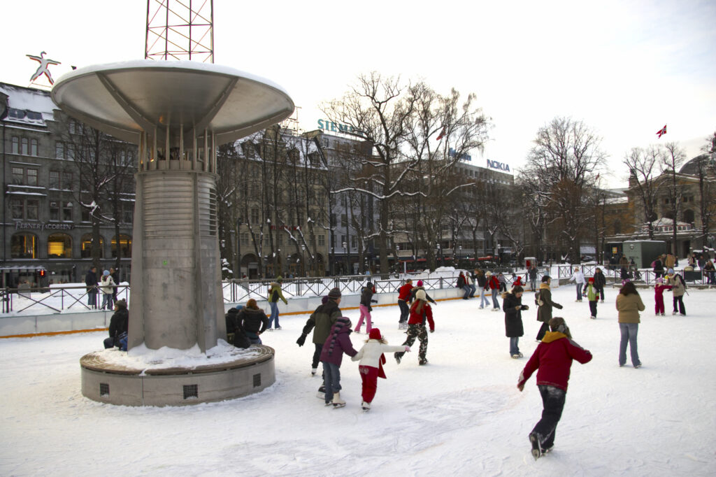 Norway, Oslo, Oslo City. Children and adults enjoying the open air ice rink near the National Theatre in the city of Oslo