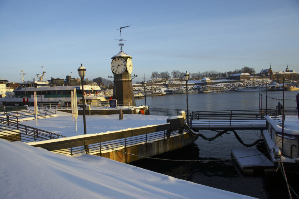 Norway, Oslo, Oslo City. Late afternoon winter light illuminates the snow coverered Aker Quay and the Oslofjorden Fjord.