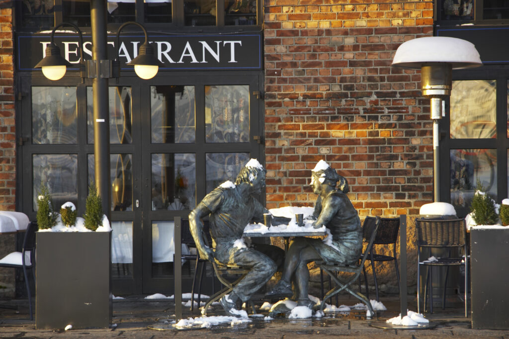 Norway, Oslo, Oslo City. Metal figures outside a quayside restaurant on the Aker Quay near the Oslofjorden Fjord.
