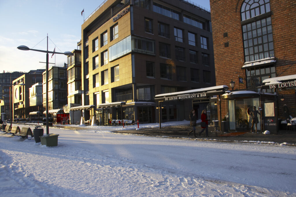 Norway, Oslo, Oslo City. Late afternoon winter light illuminates the snow coverered Aker Quay and the Oslofjorden Fjord.
