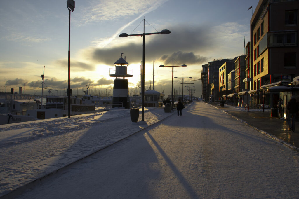 Norway, Oslo, Oslo City. Late afternoon winter light illuminates the snow coverered Aker Quay and the Oslofjorden Fjord.