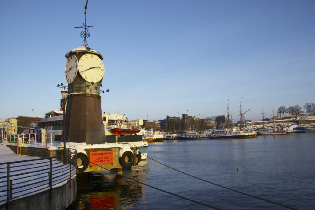 Norway, Oslo, Oslo City. Late afternoon winter light illuminates the snow coverered Aker Quay and the Oslofjorden Fjord.