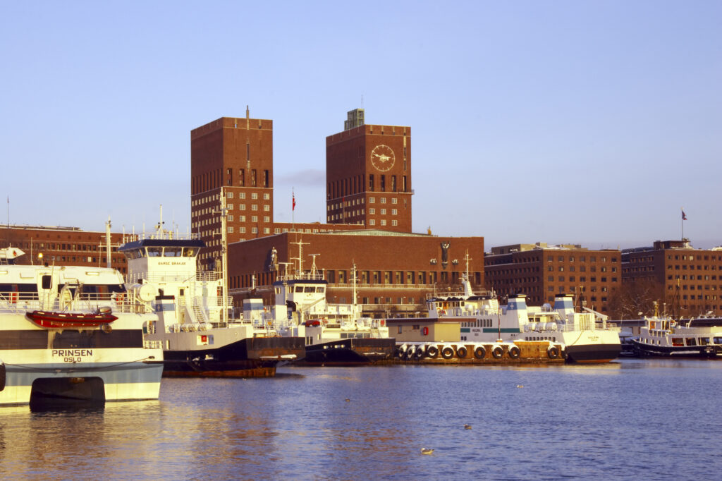 Norway, Oslo, Oslo City. Late afternoon winter light illuminates the snow coverered Aker Quay and the Oslofjorden Fjord.