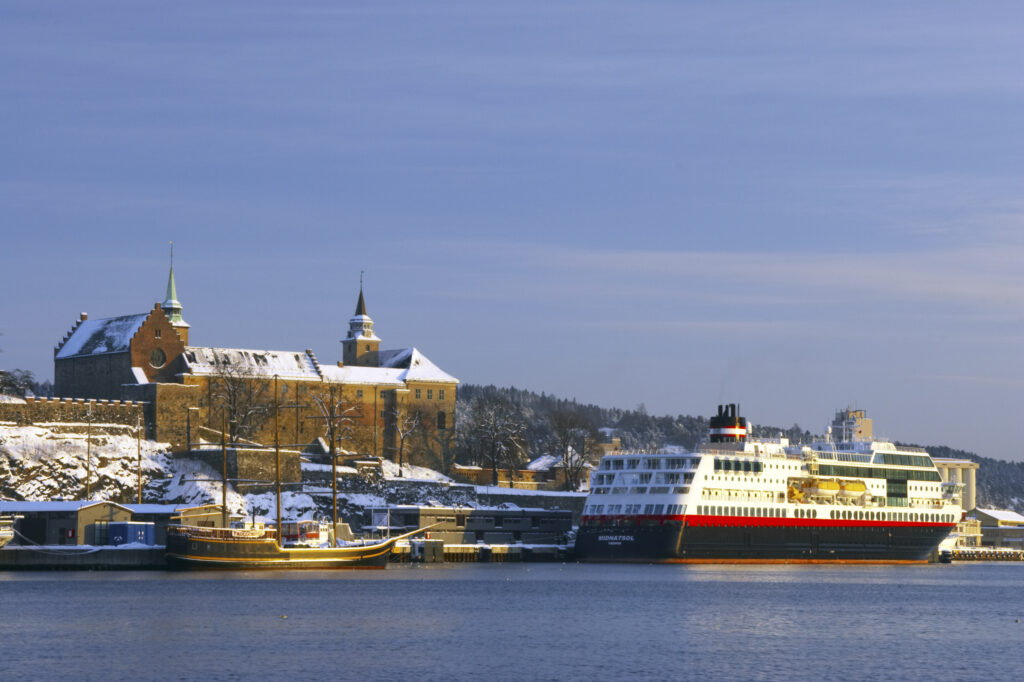 Norway, Oslo, Oslo City. Late afternoon winter light illuminates the snow coverered Aker Quay and the Oslofjorden Fjord.