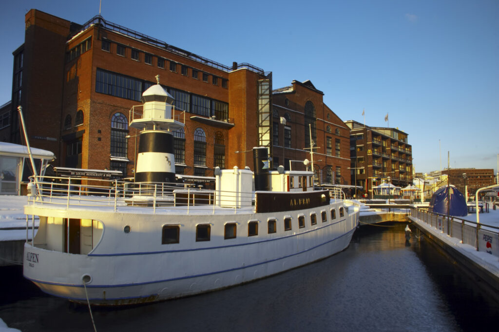 Norway, Oslo, Oslo City. Late afternoon winter light illuminates the snow coverered Aker Quay and the Oslofjorden Fjord.