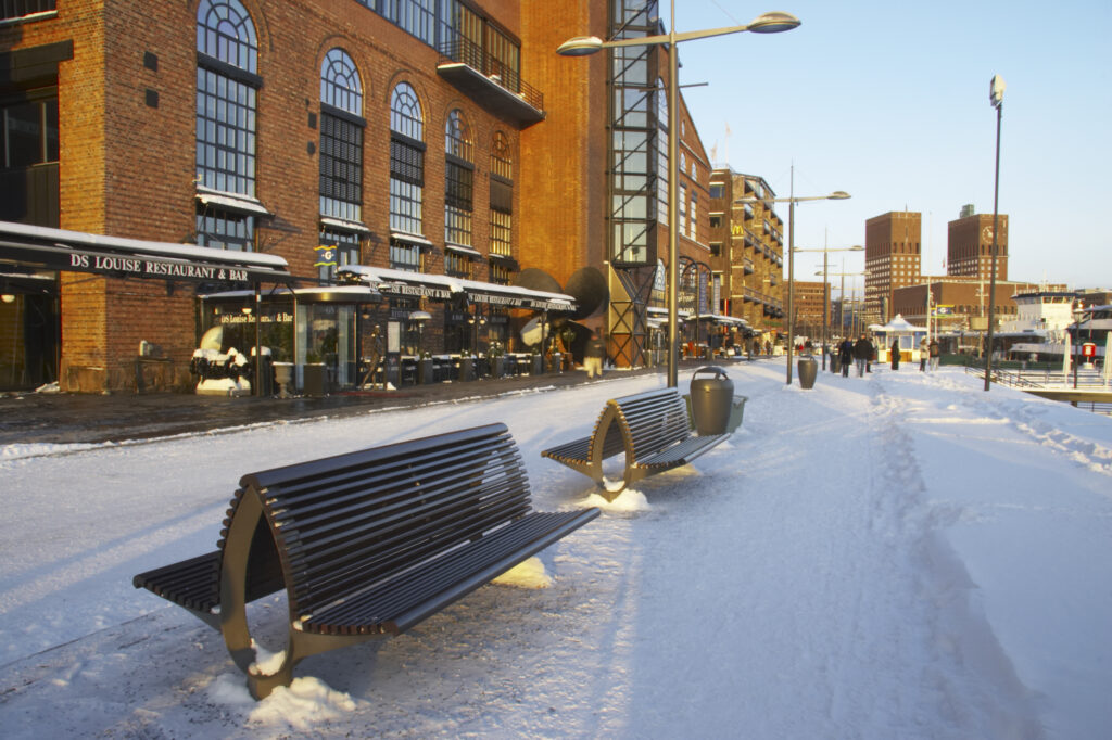 Norway, Oslo, Oslo City. Late afternoon winter light illuminates the snow coverered Aker Quay and the Oslofjorden Fjord.
