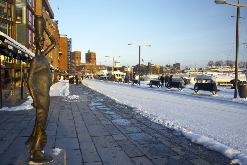Norway, Oslo, Oslo City. Late afternoon winter light illuminates the snow coverered Aker Quay and the Oslofjorden Fjord.