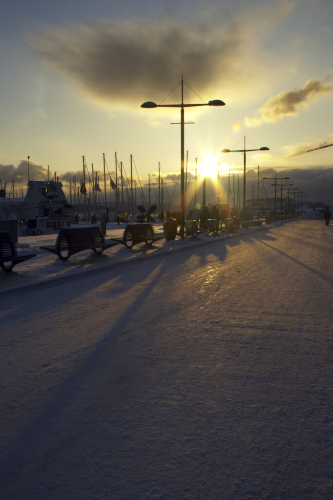 Norway, Oslo, Oslo City. Sunset over the waters of the Oslofjorden Fjord, and surrounding snow covered Aker Quay.