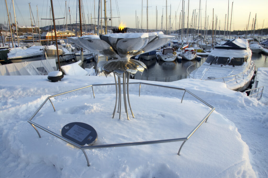 Norway, Oslo, Oslo City. Flames of peace monument on the snow coverered Aker Quay and Oslofjorden Fjord