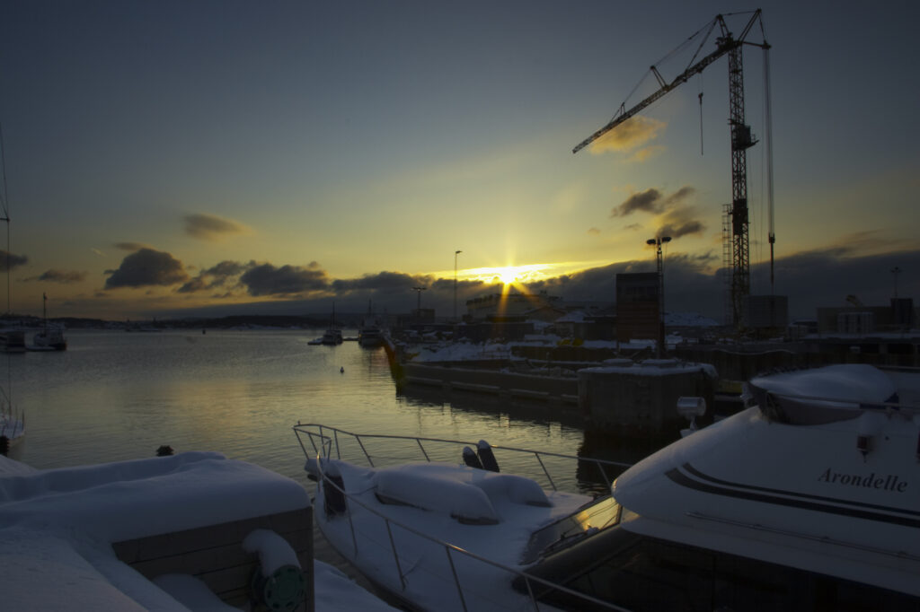 Norway, Oslo, Oslo City. Late afternoon winter light illuminates the snow coverered Aker Quay and the Oslofjorden Fjord.