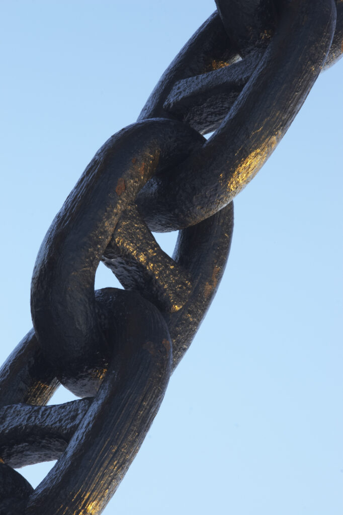 Norway, Oslo, Oslo City. Links on an anchor statue on the snow coverered Aker Quay and Oslofjorden Fjord