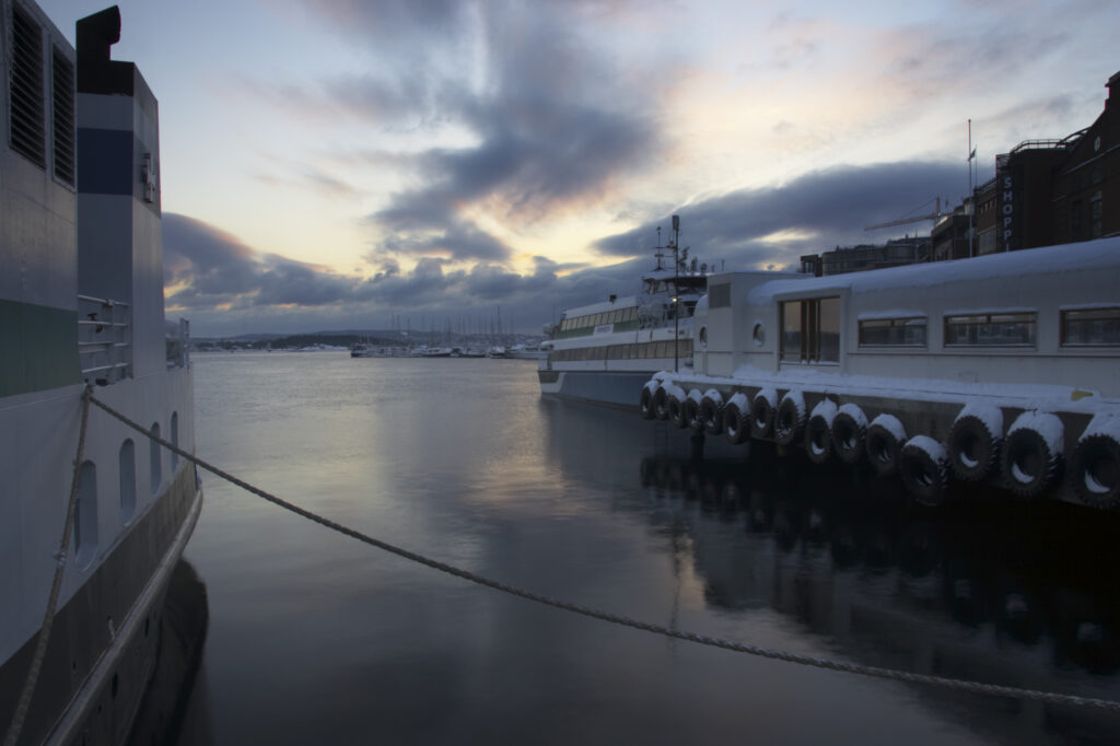 Norway, Oslo, Oslo City. Sunset behind boats moored at the Aker Quay on the Oslofjorden Fjord, near the heart of Oslo city