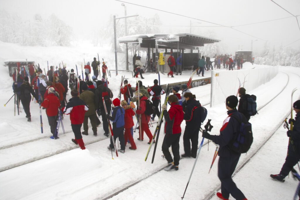 Norway, Oslo, Frognerseteren Skiers and snow boarders cross the metro train line at the Frognerseteren station near the Tryvann Skifield