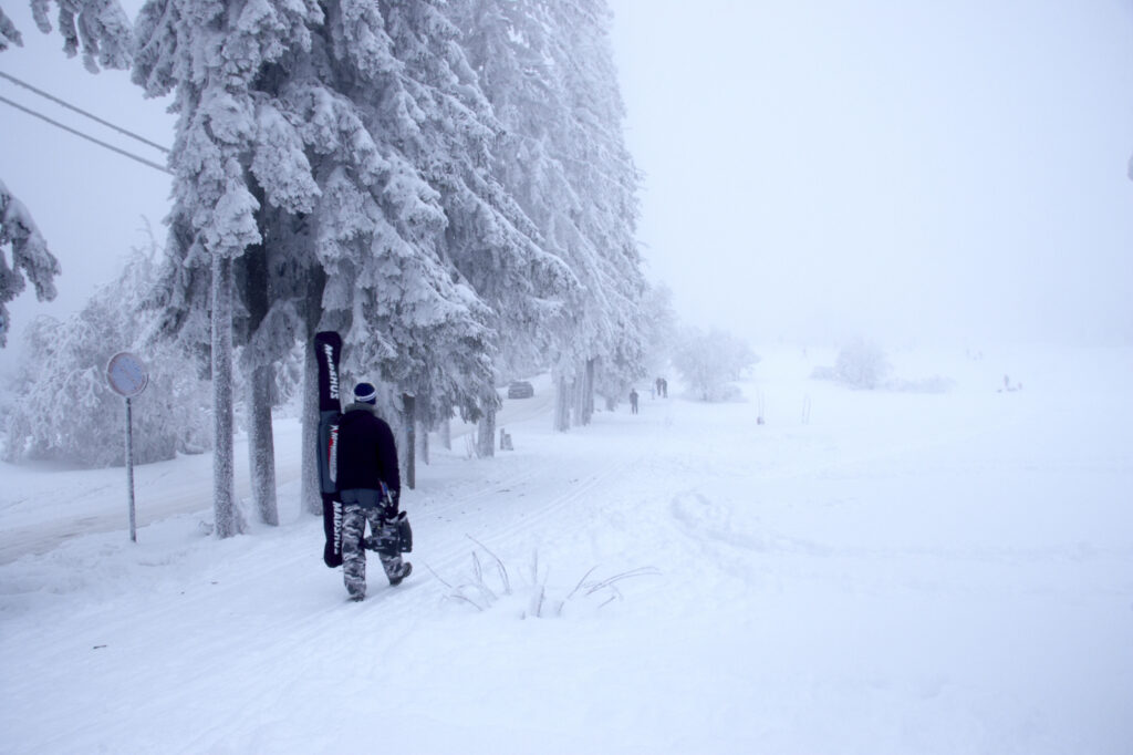 Norway, Oslo, Holmenkollen. A snow boarder walks up to the upper slopes of the Tryvann Skifield, in the Holmenkollen area.