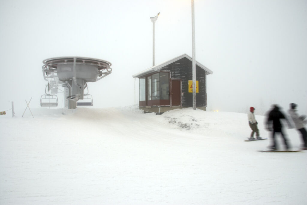Norway, Oslo, Holmenkollen. Snow boarders skiing of a chairlift in the Tryvann Skifield, in the Holmenkollen area.