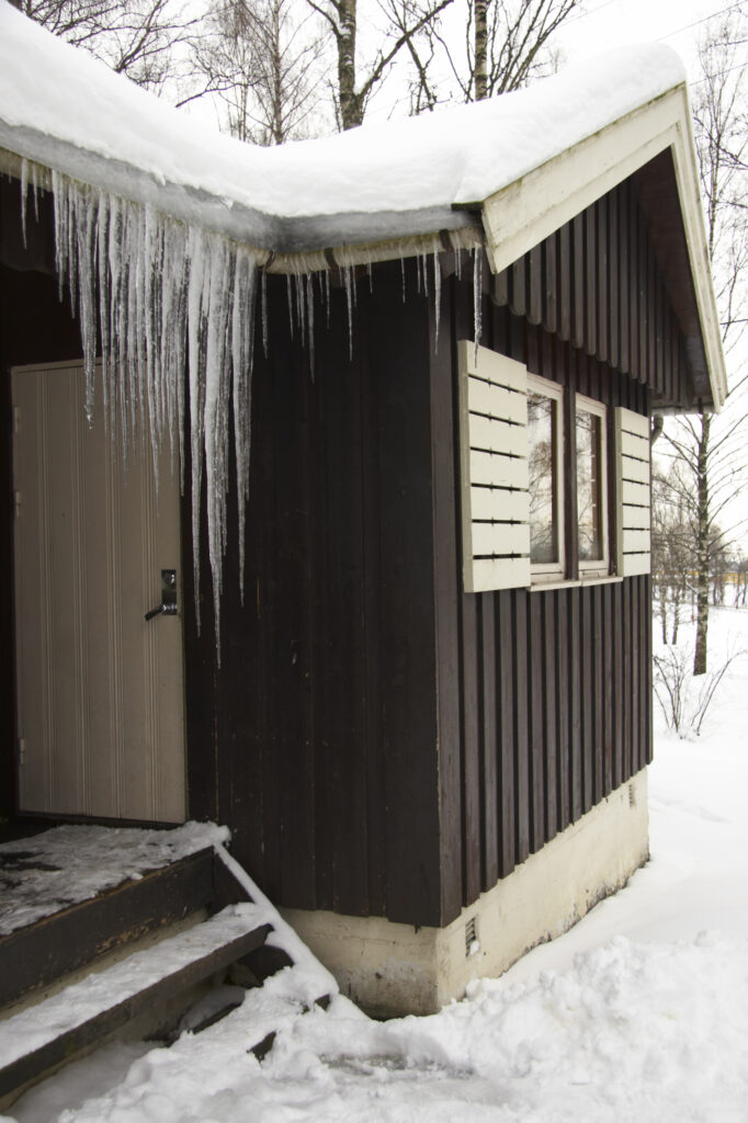 Norway, Oslo, Oslo City. Icicles and snow covered wooden camping huts / cabins in the Bogstad camping ground in Oslo city.
