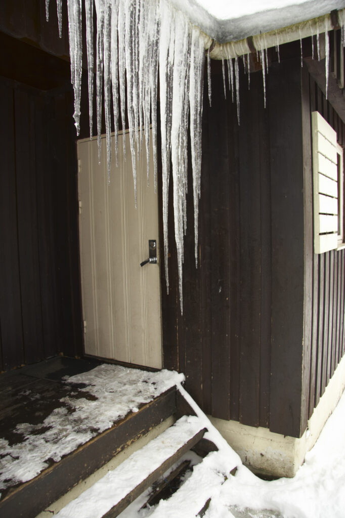 Norway, Oslo, Oslo City. Icicles and snow covered wooden camping huts / cabins in the Bogstad camping ground in Oslo city.