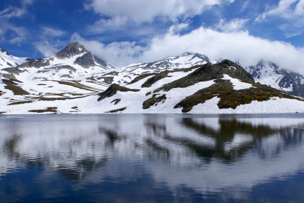 Switzerland Valais Val Ferret. Snow covered peaks of mountains reflected in an alpine lake located near La Fouly