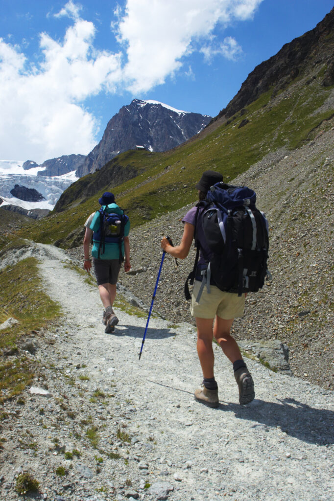 Switzerland Valais, Schonbielhutte. Hikers walking along a trail heading towards Schonbielhutte hut alongside the Zmuttgletscher