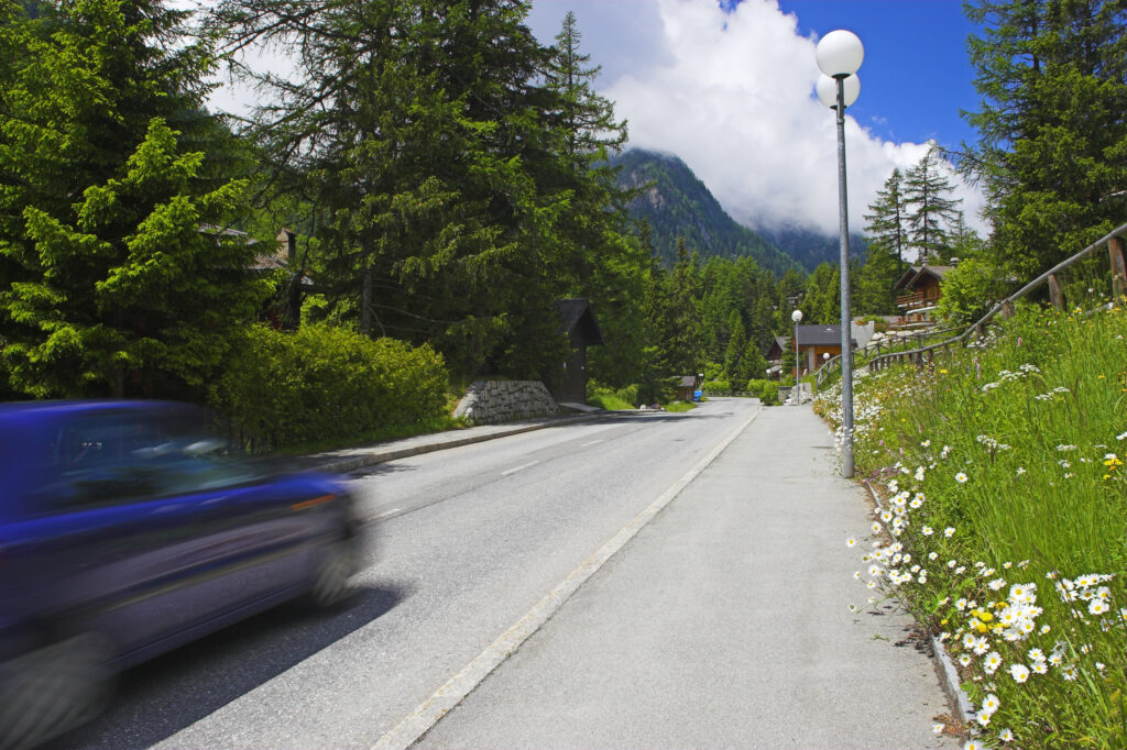 Switzerland, Valais, Champex. A car speeds down a quiet road in the sleepy village of Champex.
