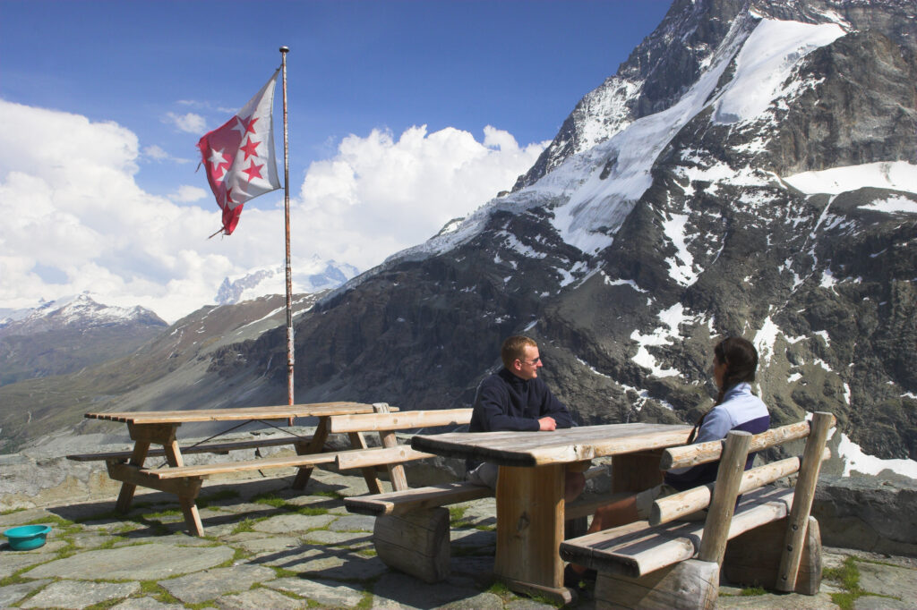 Switzerland, Valais, The Matterhorn. A brother and sister enjoy the fine views of the alps from benches outside Schonbielhutte