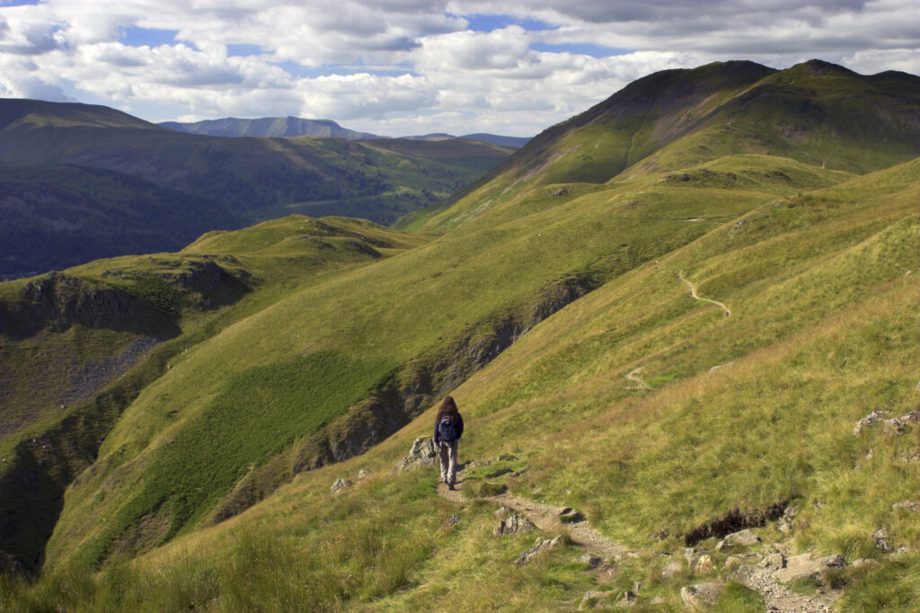 England, Cumbria, Lake District National Park. Female hiker walking along public footpath in Patterdale Common