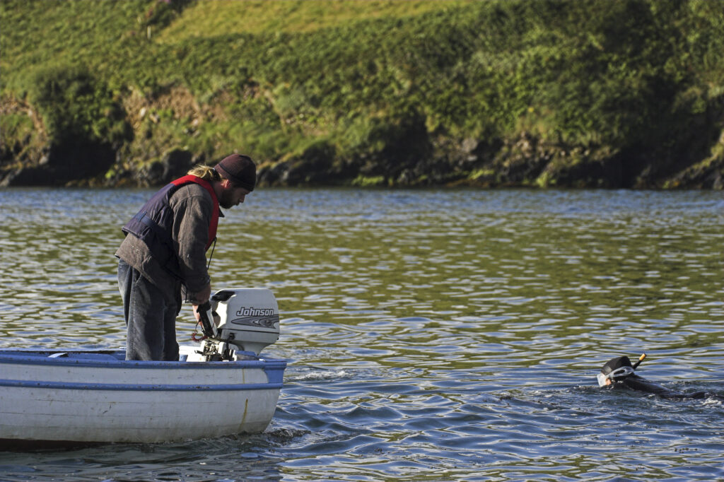 Ireland County Kerry Dingle Peninsula Girl snorkling and small boat in Dingle Bay near Dingle looking for Fungi the dolphin