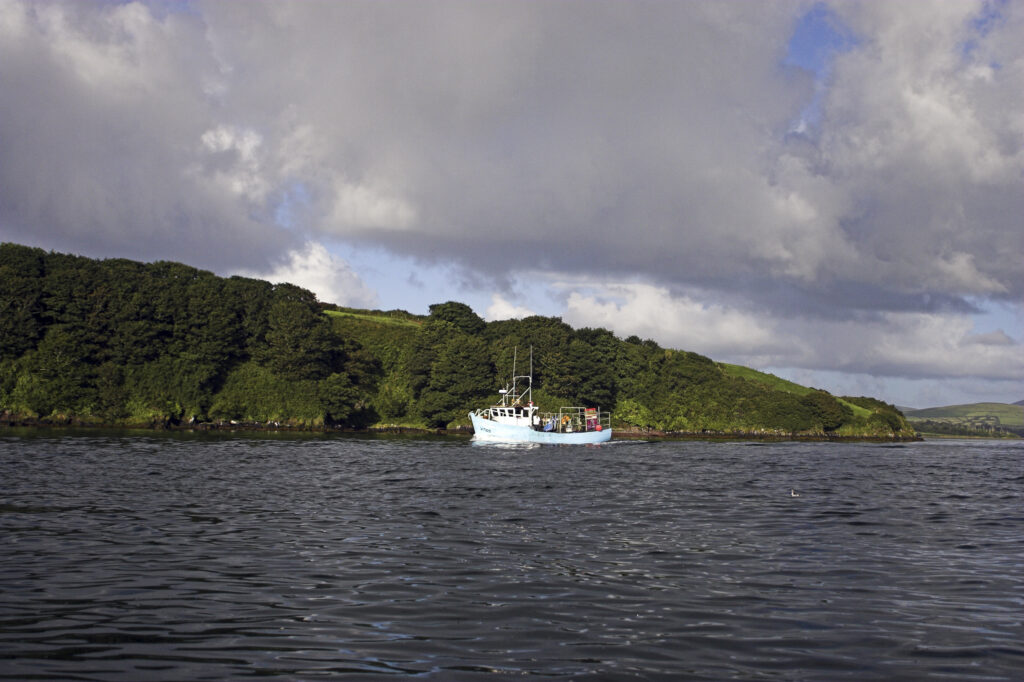 Ireland County Kerry Dingle Peninsula A fishing boat heading out over Dingle Bay near Dingle