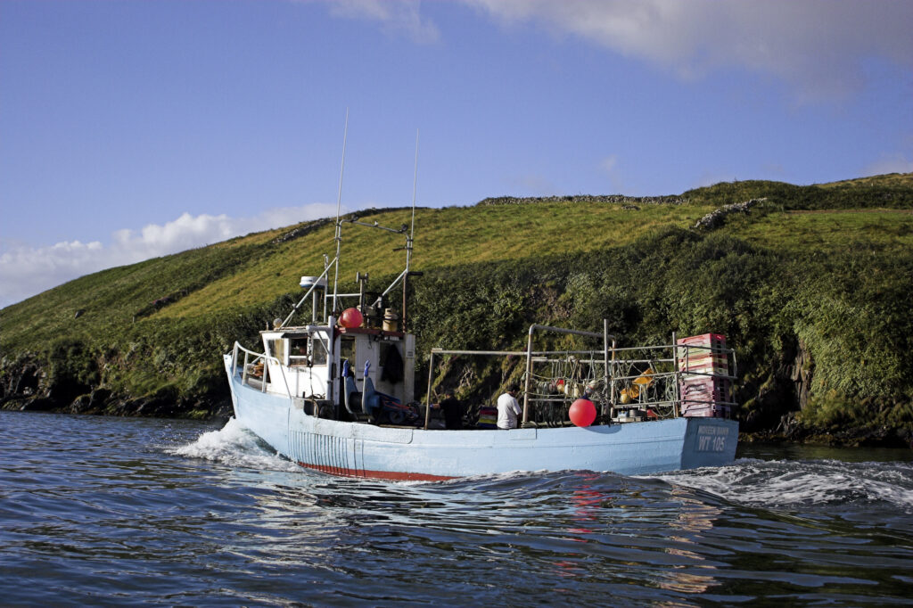 Ireland County Kerry Dingle Peninsula A fishing boat heading out over Dingle Bay near Dingle