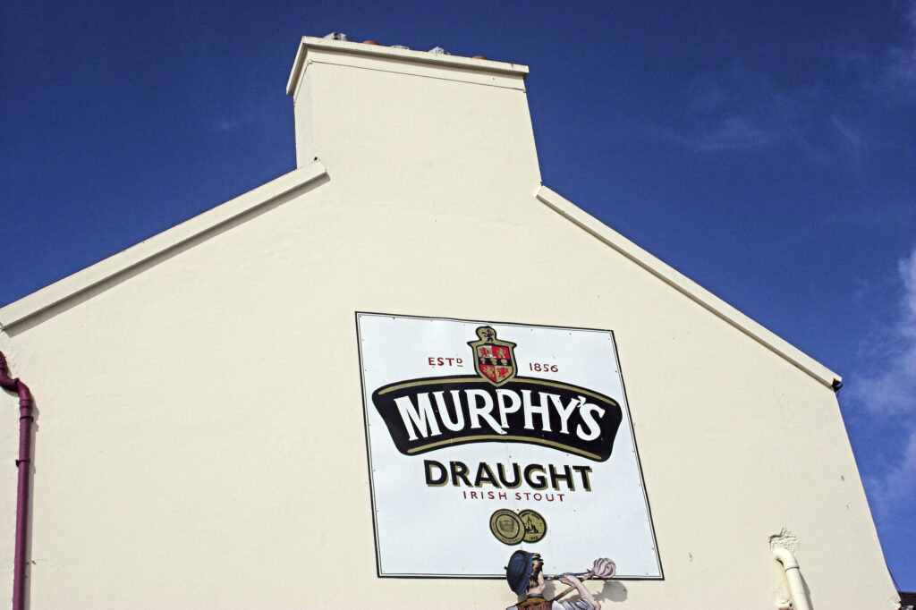 Ireland County Kerry Dingle A large sign advertising Murphys stout on the side of a pub in Dingle