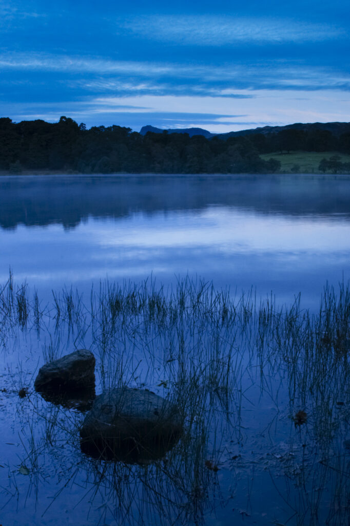 England, Cumbria, Lake District National Park Reflections of typical lake district scenary in the still waters of Loughrigg Tarn