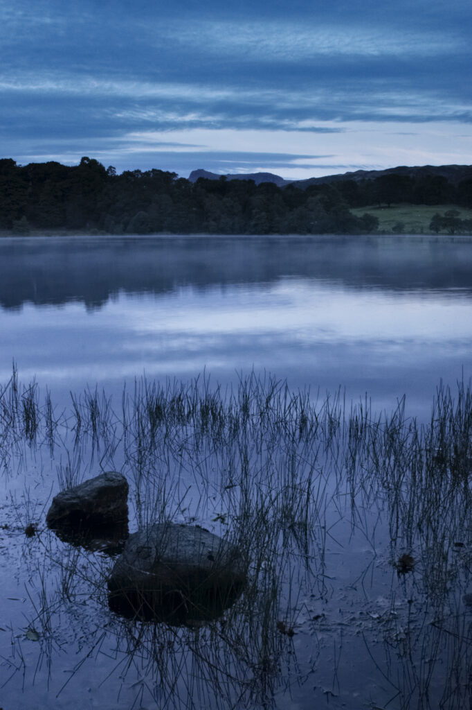 England, Cumbria, Lake District National Park Reflections of typical lake district scenary in the still waters of Loughrigg Tarn