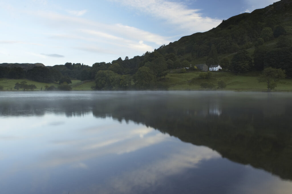 England, Cumbria, Lake District National Park Reflections of typical lake district scenary in the still waters of Loughrigg Tarn