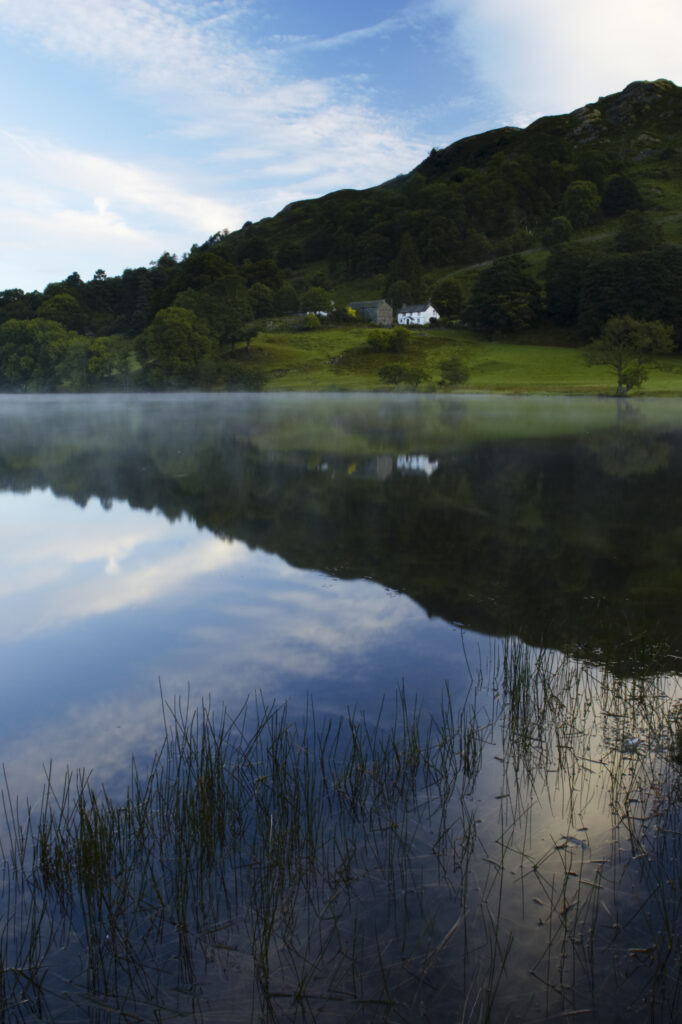 England, Cumbria, Lake District National Park Reflections of typical lake district scenary in the still waters of Loughrigg Tarn