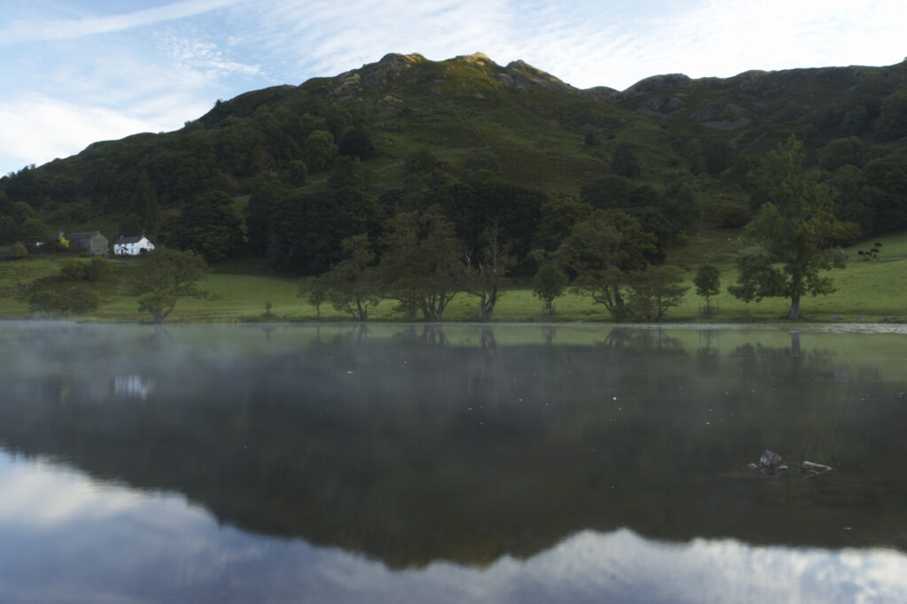 England, Cumbria, Lake District National Park Reflections of typical lake district scenary in the still waters of Loughrigg Tarn