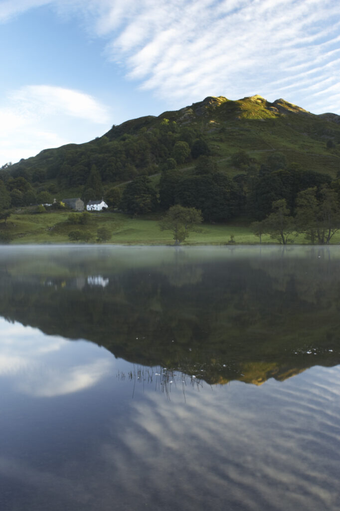 England, Cumbria, Lake District National Park Reflections of typical lake district scenary in the still waters of Loughrigg Tarn