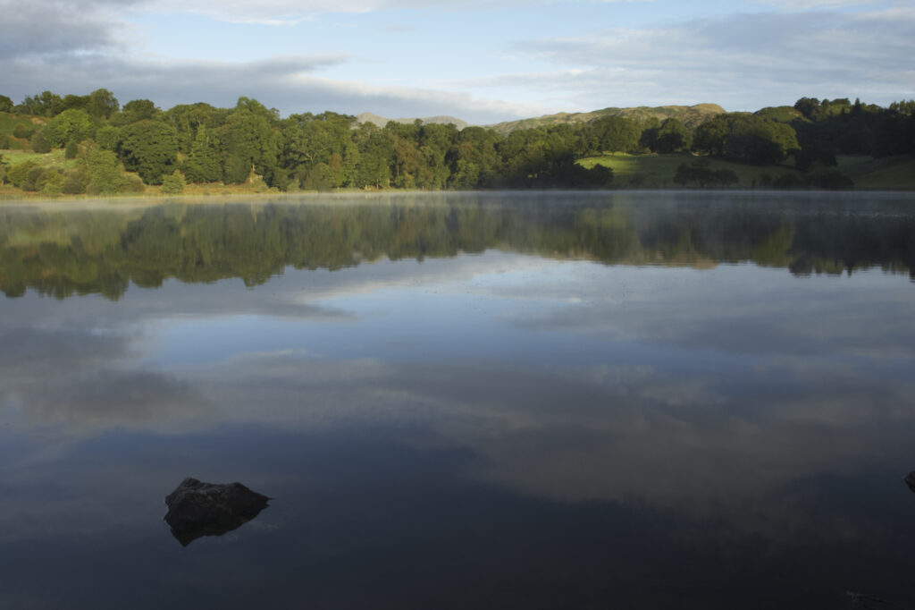 England, Cumbria, Lake District National Park Reflections of typical lake district scenary in the still waters of Loughrigg Tarn