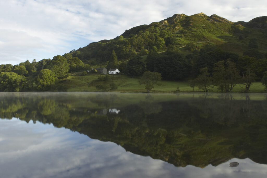England, Cumbria, Lake District National Park Reflections of typical lake district scenary in the still waters of Loughrigg Tarn